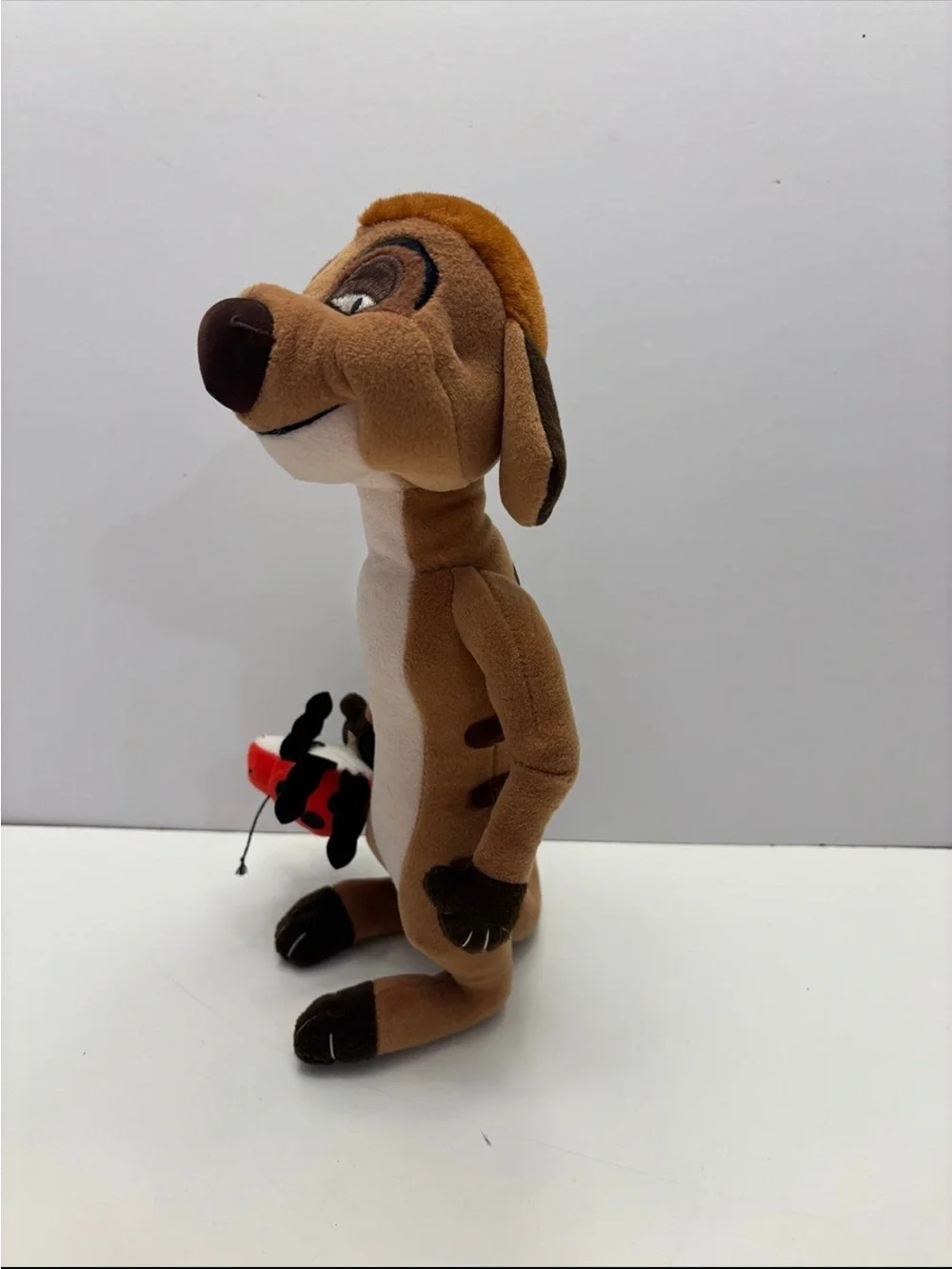 Disney The Lion King Timon plush toy holding a small red ladybug